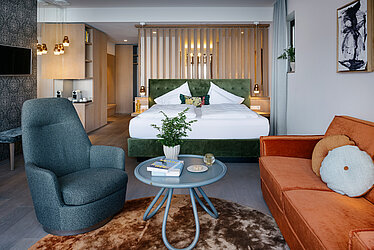 Großzügige Suite mit Doppelbett, Wohnbereich, Sesseln und moderner Einrichtung am Traunsee