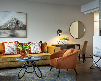 Wohnbereich mit Sofa, Sessel und Schreibtisch in moderner Suite am Traunsee