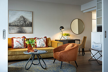Wohnbereich mit Sofa, Sessel und Schreibtisch in moderner Suite am Traunsee
