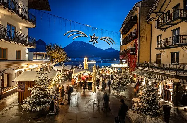 Christkindlmarkt am Wolfgangsee mit Bergpanorama und Sternenlicht.