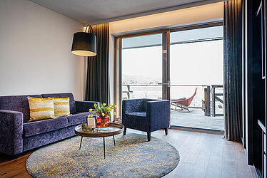 Wohnbereich mit Sofa, Sessel und Balkon mit Seeblick am Traunsee